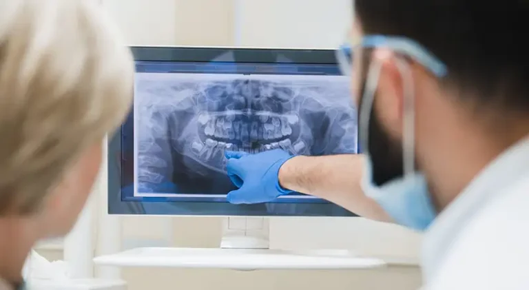 Two dentists review x-rays of a patient's mouth.