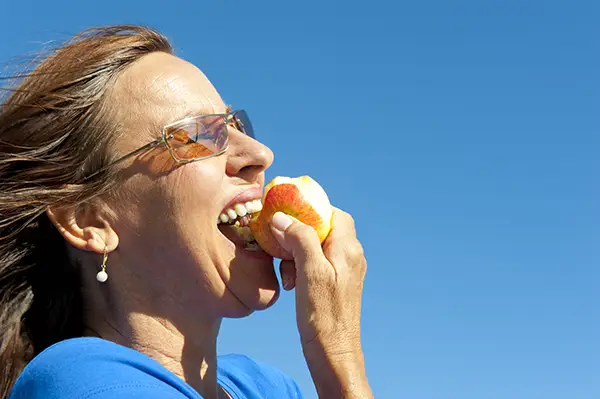 dental implant patient biting into an apple