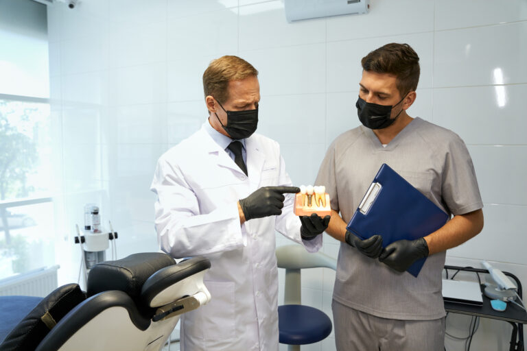 A certified dental technician talks with a dentist about a tooth restoration using a model.