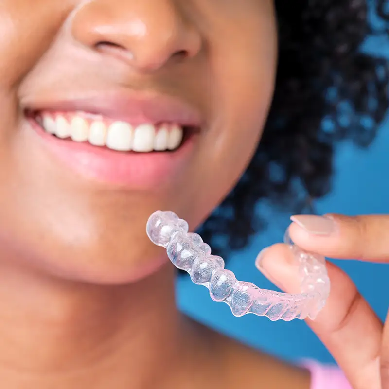 Woman holding up clear aligner