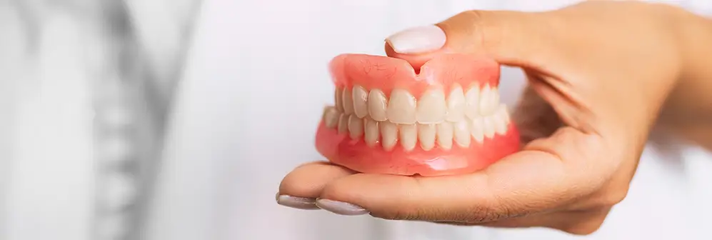 Virginia Beach dentist holding set of full dentures