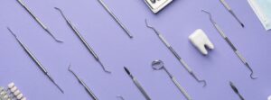 Tray with dentist's tools and masks on a purple background for tooth replacements.