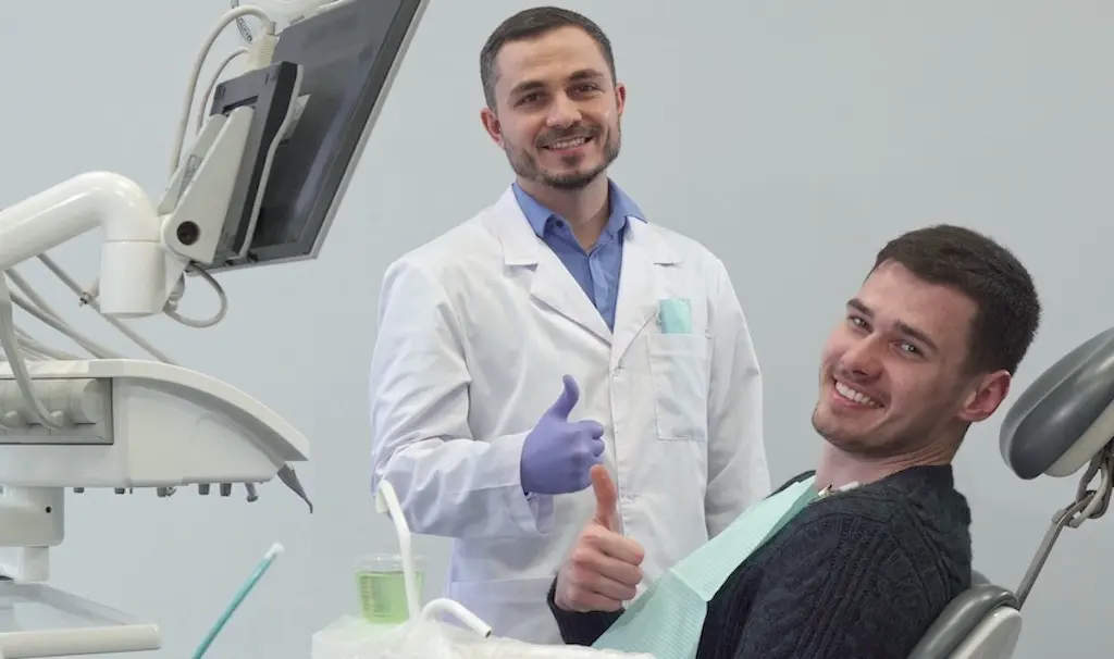 A smiling dentist and patient are giving thumbs up at The Foleck Center in Virginia after a successful dental implants consultation and treatment.