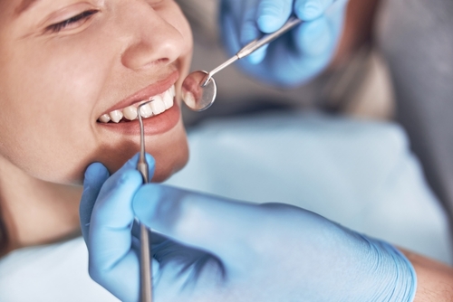 Woman showing her teeth while getting dental services from a dentist at a cosmetic dentistry clinic.