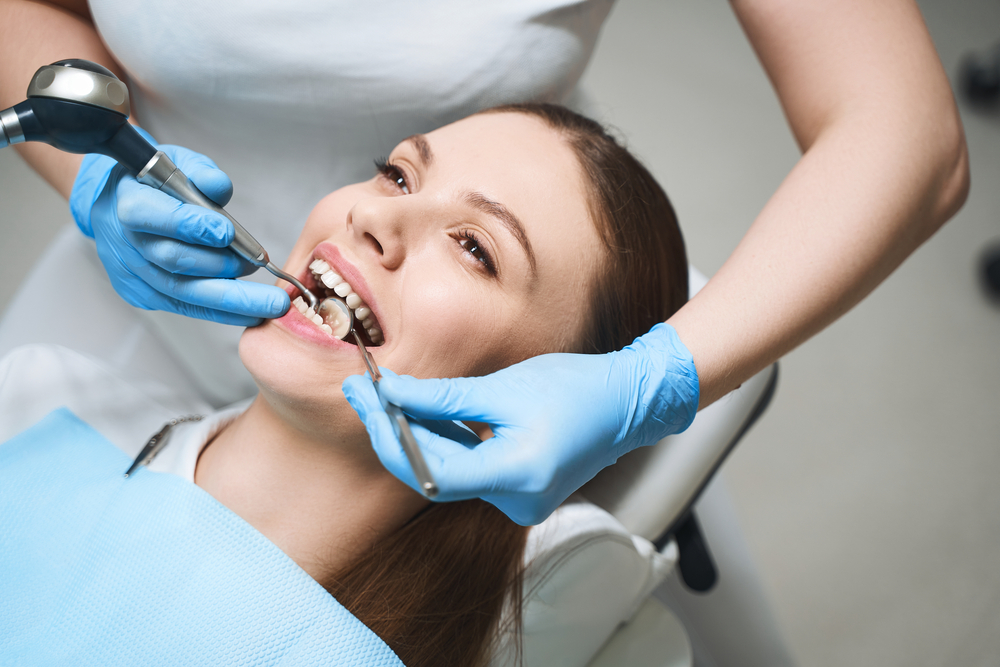 Attractive female is visiting dentist and being given root canal by specialist with modern equipment