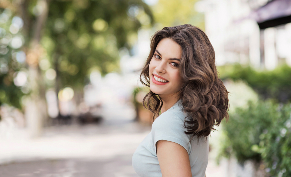 Confident Smile Outdoors: Virginia Beach Implant Patient Woman smiling confidently outdoors after dental implant treatment in Virginia Beach