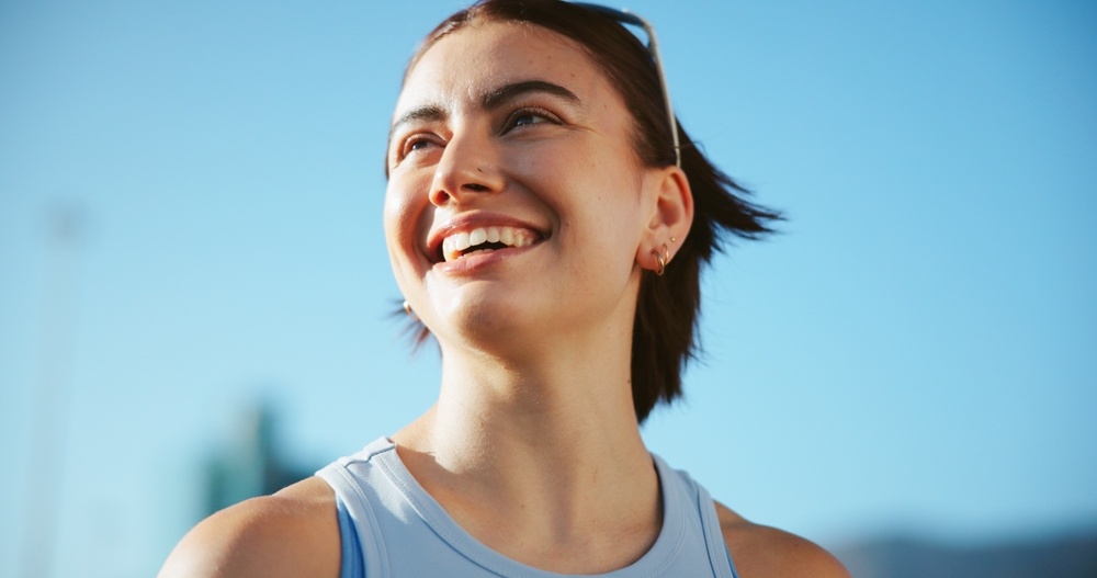 Break, runner or happy woman in city thinking of fitness, marathon training and exercise health. Low angle, ideas or athlete in urban town for workout performance, outdoor jog or sports challenge