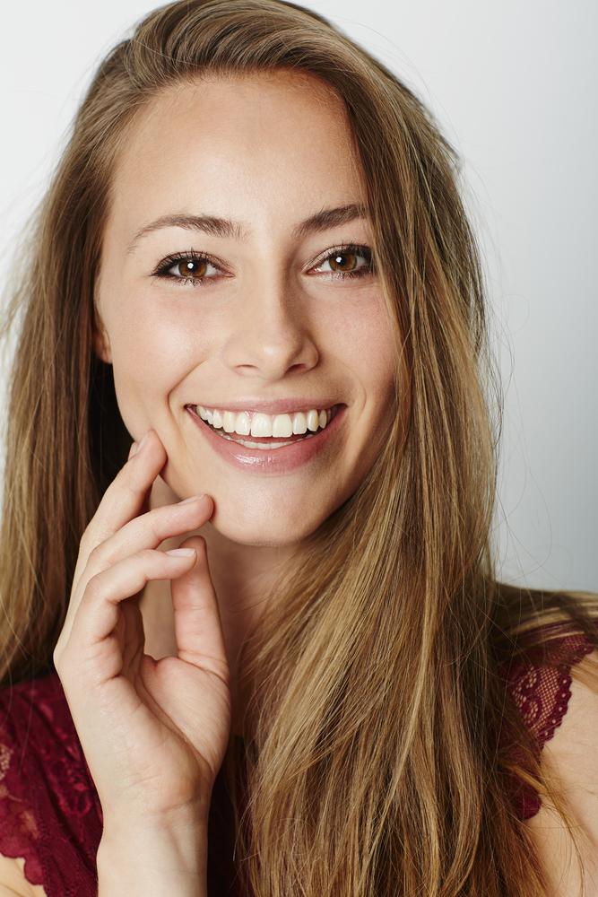 Healthy smile: gum disease prevention in Hampton Roads Woman with long brown hair smiling with her hand near her chin