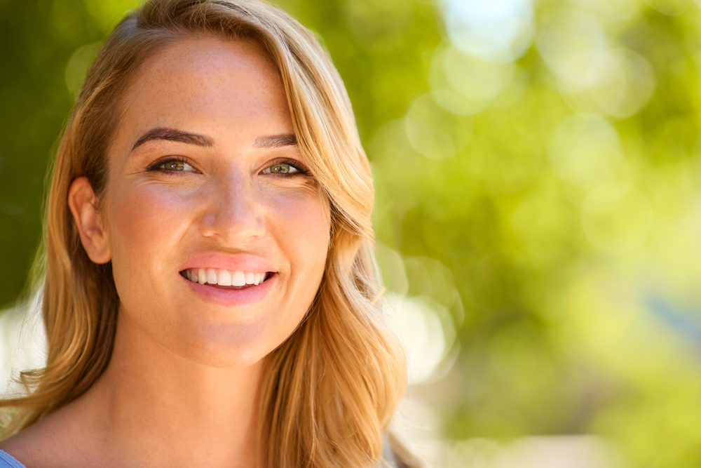 Close Up Portrait Of Smiling Woman's Face Outside Relaxing In Countryside Looking At Camera