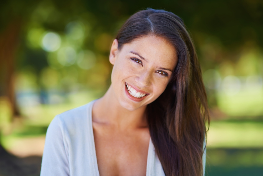 Face, smile and portrait of a woman happy in a park in summer for beauty, excited and confident in nature. Head, garden and female person or model outdoor with freedom, happiness and style