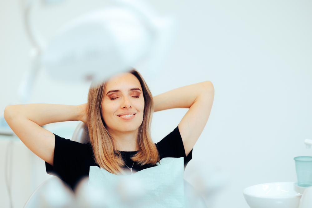 Happy Relaxed Patient Sitting in a Dental office. Carefree woman happy with the results after dental treatment