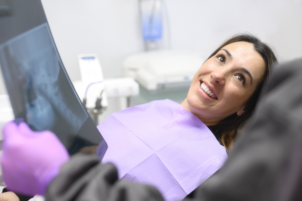 Patient smiling while looking at her dental X-ray in the treatment chair 
