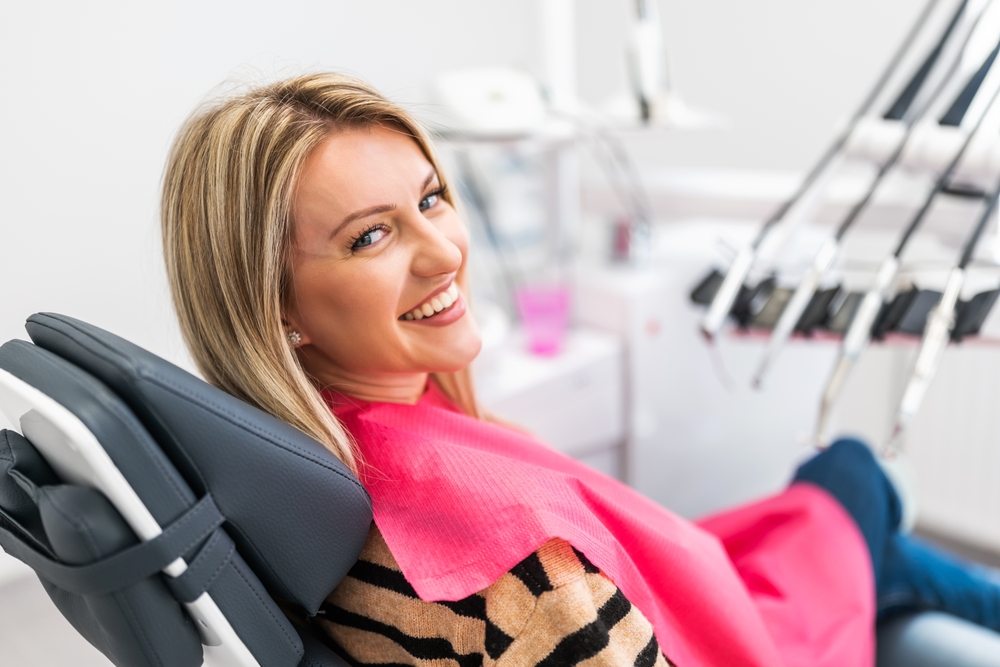 Happy young woman in modern dental clinic. She is looking at camera and smiling.