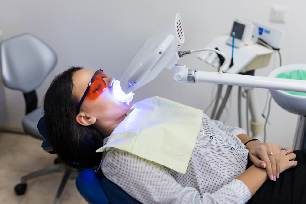 Laser bleaching teeth at dantist room. Teeth whitening for woman. Bleaching of the teeth at dentist clinic
