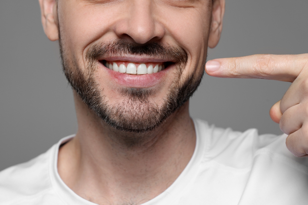Man pointing to his healthy smile with his finger