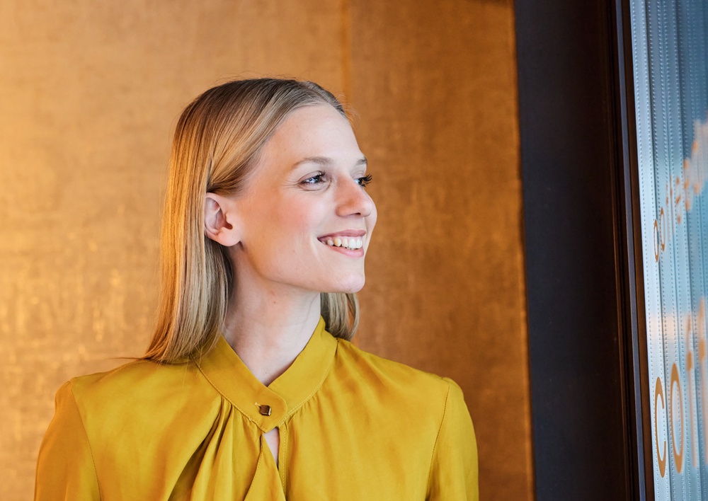 Confident smile, gum disease care in Hampton Roads Woman in a yellow blouse smiling while looking to the side indoors