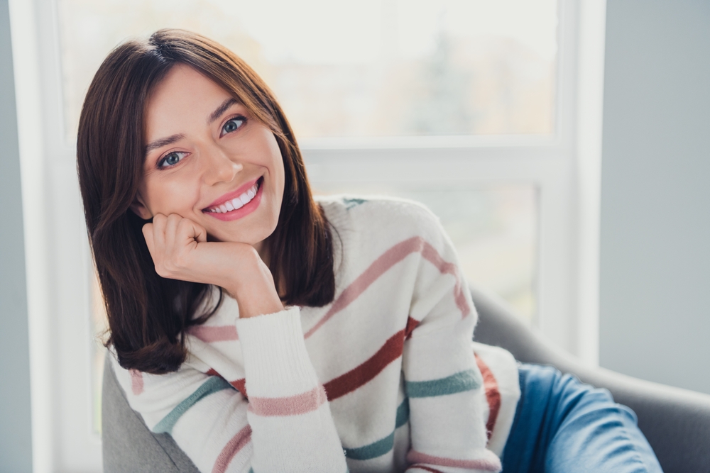 Portrait of friendly stunning girl sit chair hand touch chin beaming smile free time chill apartment inside