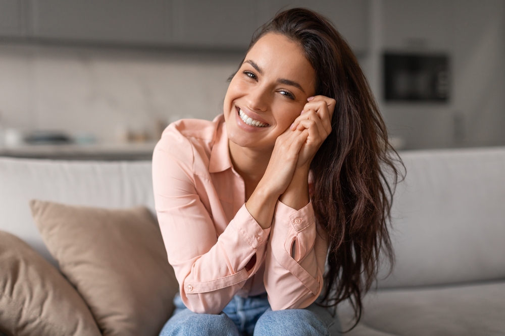 Smiling woman with a bright, whitened smile relaxing at home after teeth whitening in Hampton Roads 