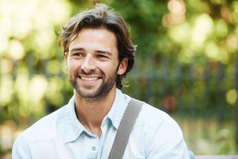 Man with a beard smiling outdoors 