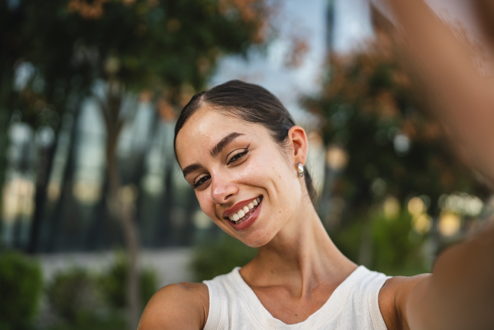 Self portrait of beautiful happy young woman stand in front building