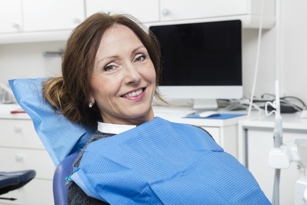 Smiling Patient Sitting At Dentist's Clinic