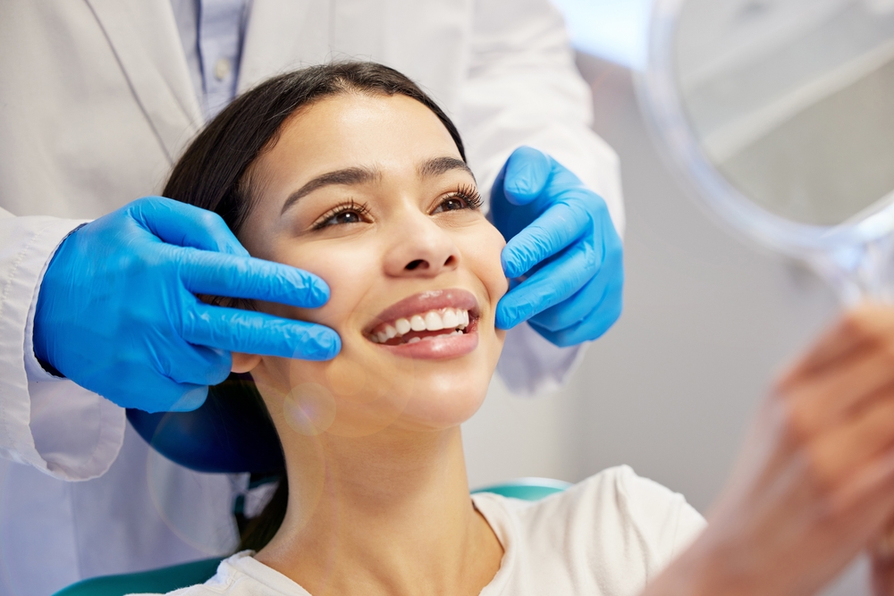 Woman, dentist and smile with mirror for dental surgery in clinic for teeth whitening and treatment with doctor. Female patient, satisfied and happy on consultation for canal procedure and oral care