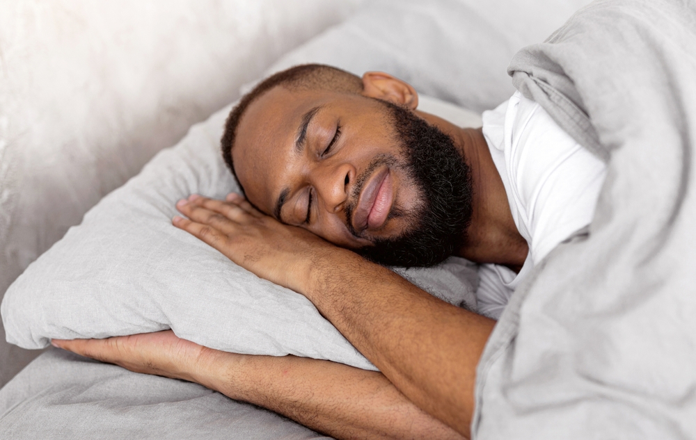 Young African American man lying in bed and sleeping