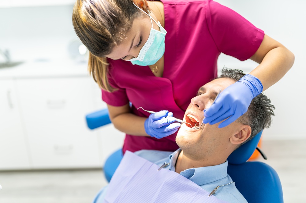 Gum health exam in Virginia Beach, Norfolk, and Hampton Dental hygienist examining a male patient's teeth with dental tools