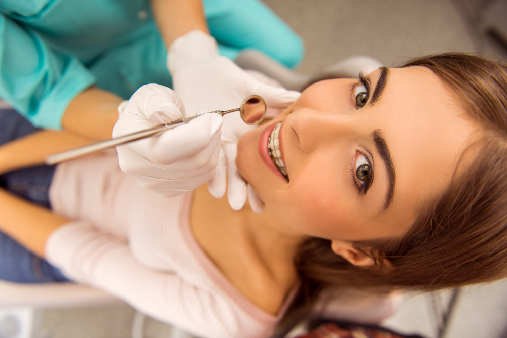 Woman with braces receiving a dental exam with mirror tool at The Foleck Center, Norfolk, VA 