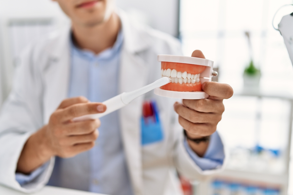 Dentist holding a model of teeth and a toothbrush while explaining sedation dentistry options in Norfolk 