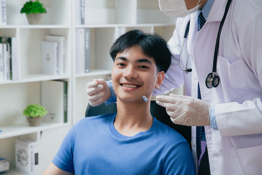 Young man getting dental checkup at dentistry, Dentist using dental equipment for examination of teeth of patient