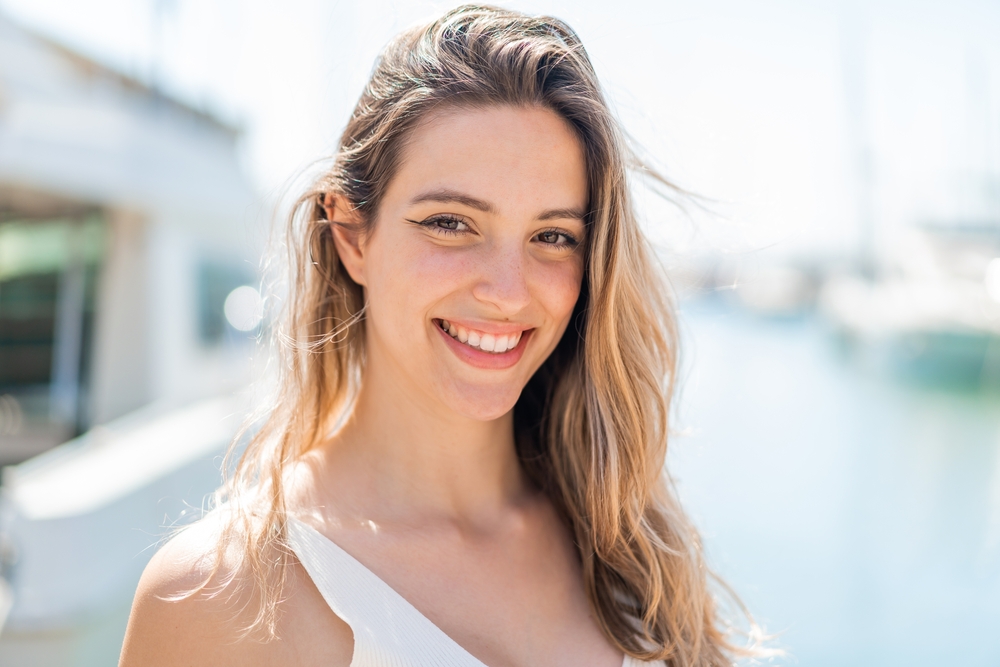Woman smiling outdoors at a marina with a bright, healthy smile 