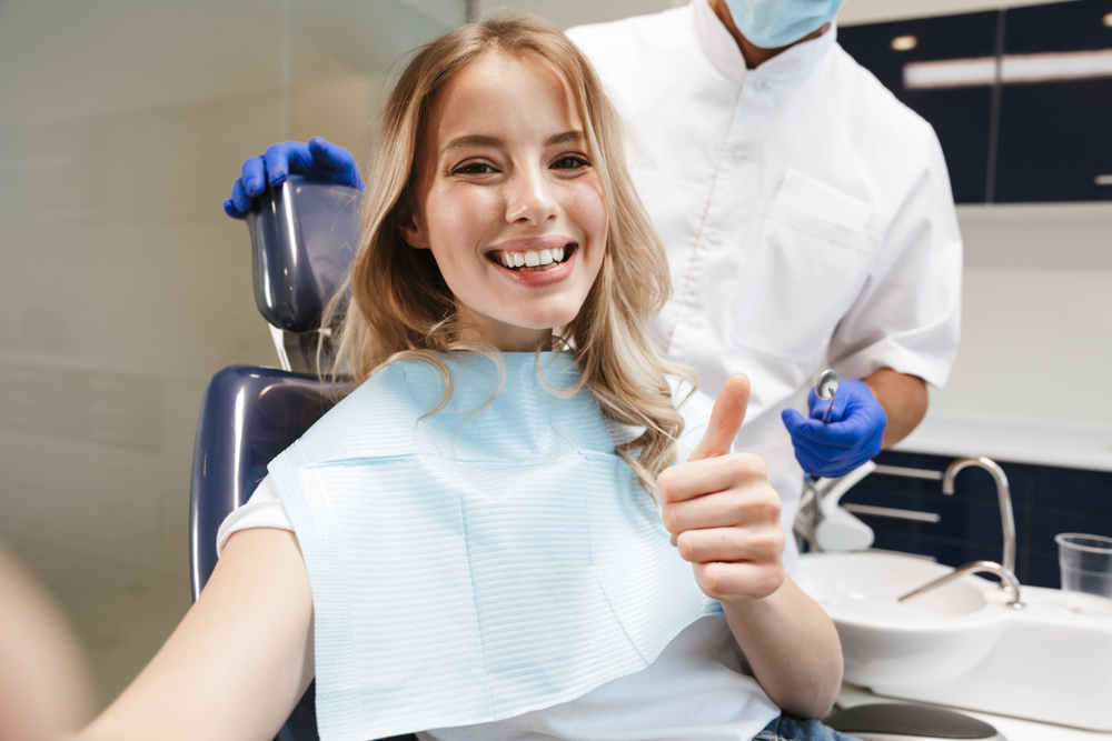 Woman giving a thumbs-up in the dental chair during a smile makeover visit in Norfolk 