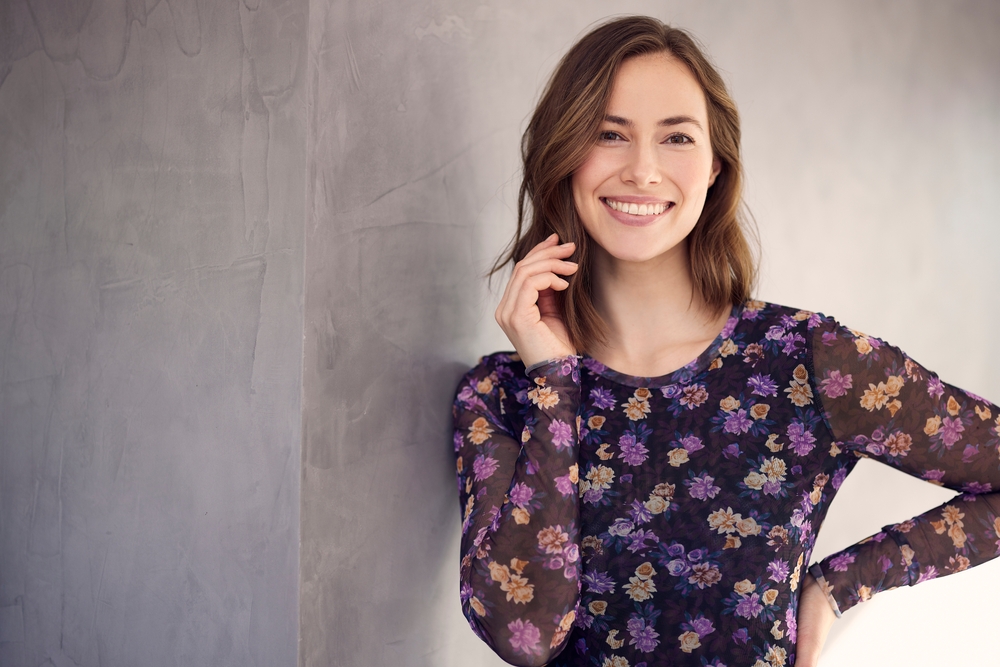 Woman smiling confidently in a floral top, representing the healthy smiles achieved through restorative dentistry in the Hampton Roads community 