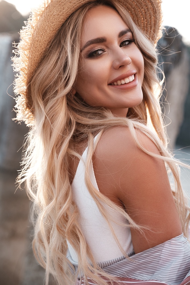 Healthy smile, gum disease care in Hampton Roads Woman in a straw hat smiling over her shoulder outdoors