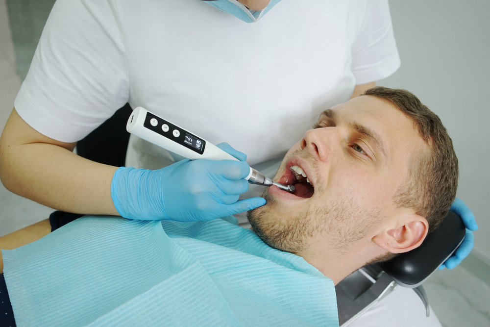 dentist makes ultrasonic cleaning of teeth to his patient 