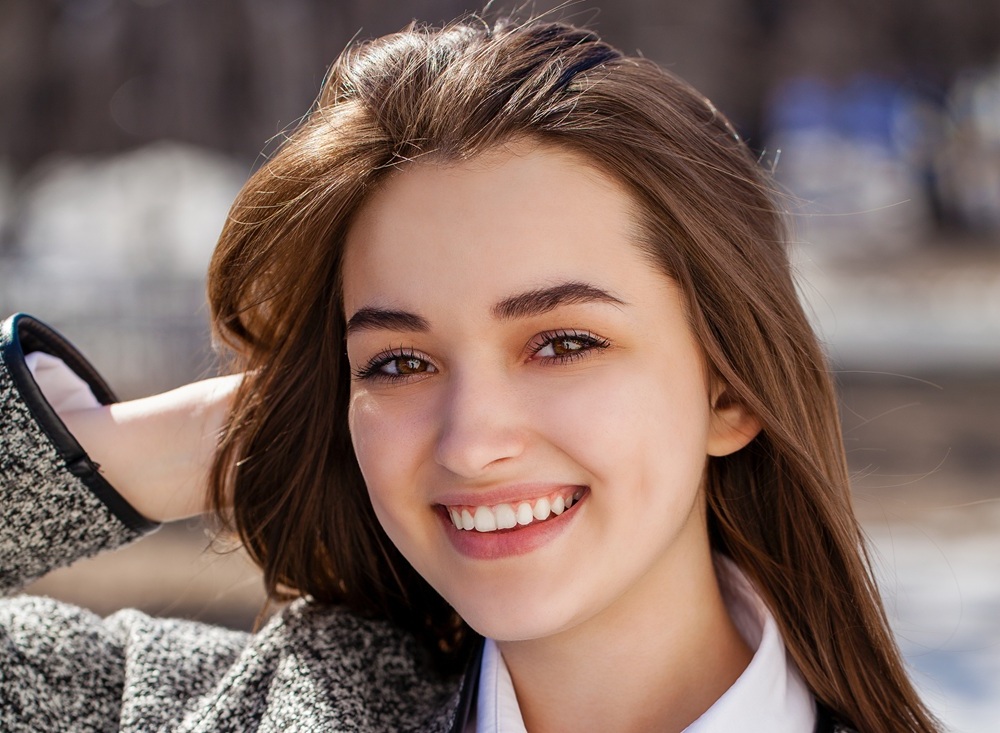 Young woman with brown hair smiling outdoors in a winter setting