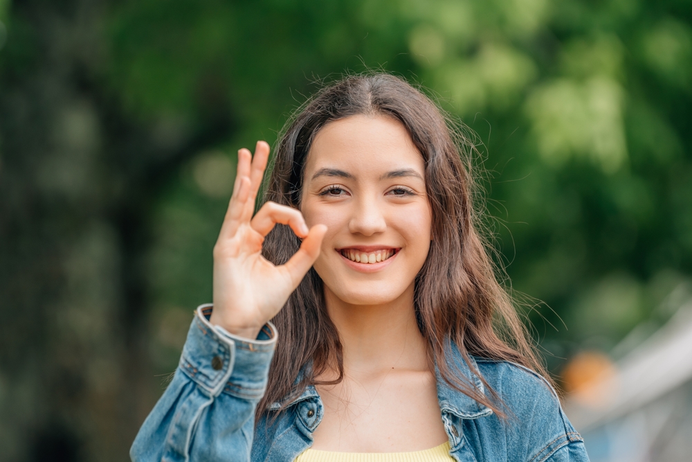 girl with phone smiling happy with satisfaction with okay sign