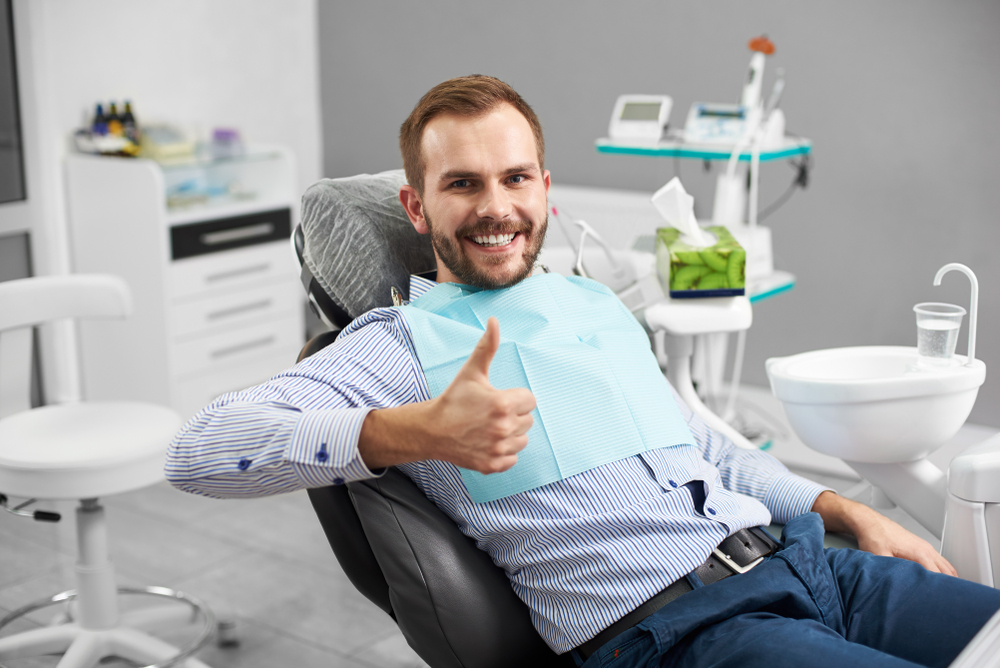 Happy male patient giving thumbs up in dental chair after comfortable sedation dentistry procedure at The Foleck Center in Virginia Beach