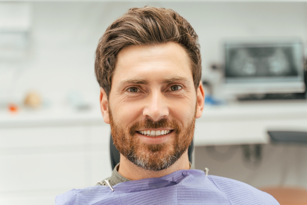 Man smiling in the dental chair after a teeth whitening procedure at a Virginia Beach dental office 