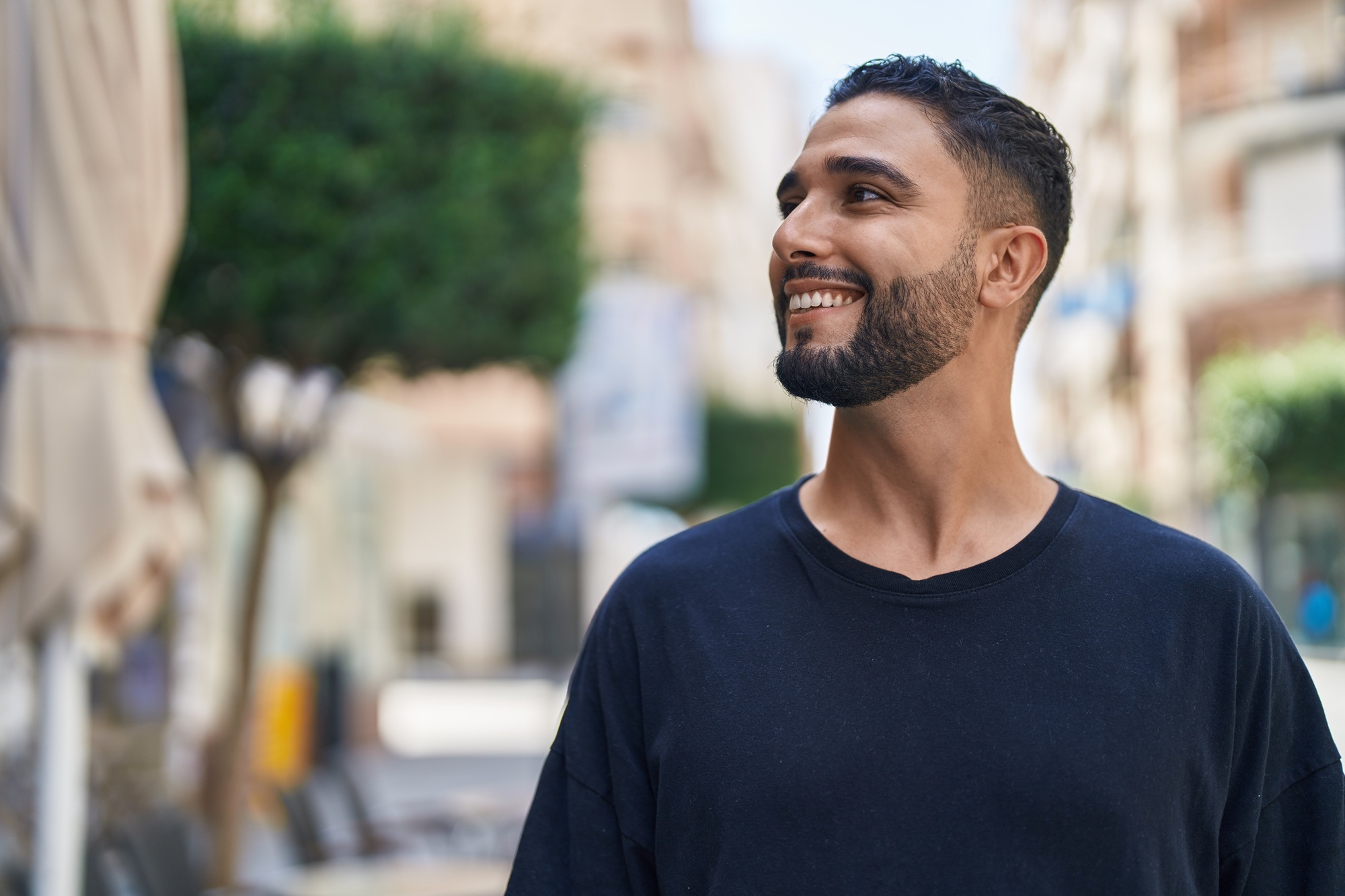 Confident smile, dentures and partials in Norfolk Young bearded man smiling while looking to the side outdoors