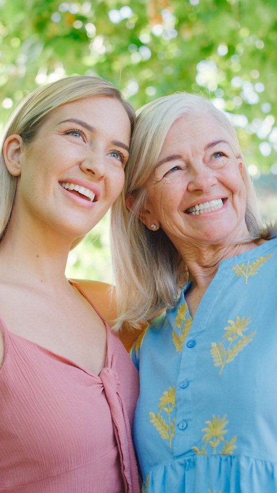 Two women, one younger and one older, smiling together outdoors