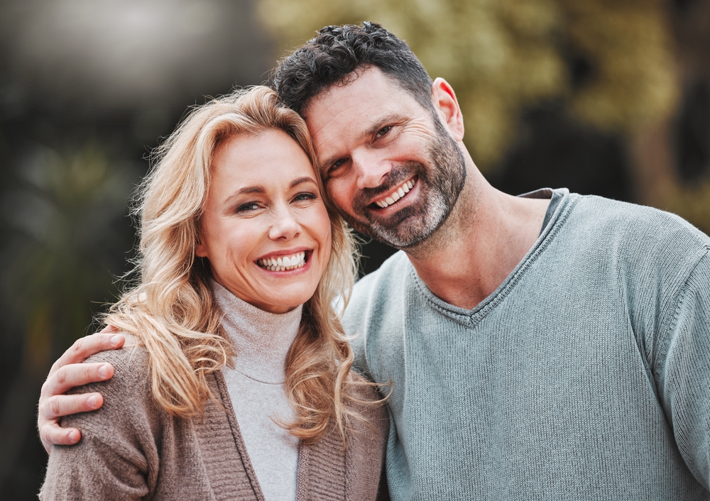 Mature couple smiling cheek to cheek outdoors