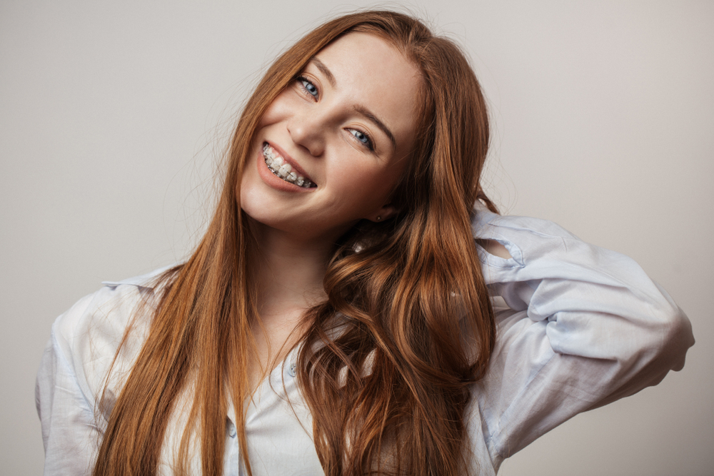 Young woman with braces smiling brightly, representing the orthodontic and restorative care available in the Norfolk community 