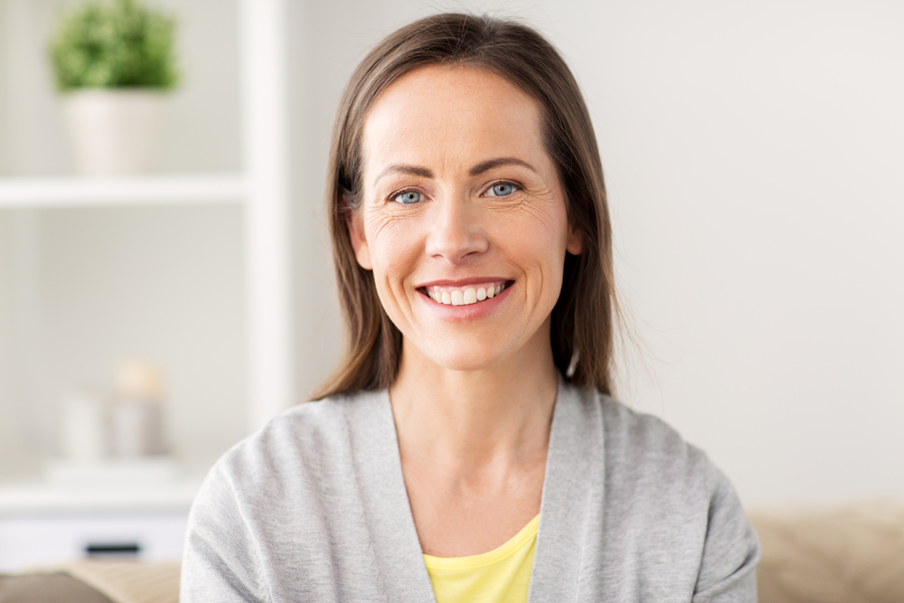 Middle-aged woman with brown hair smiling indoors 