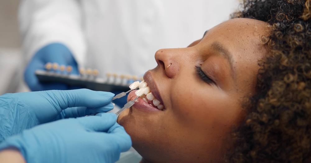 Dentist matching tooth shade with a dental guide during an implant crown consultation at The Foleck Center, Norfolk, VA 