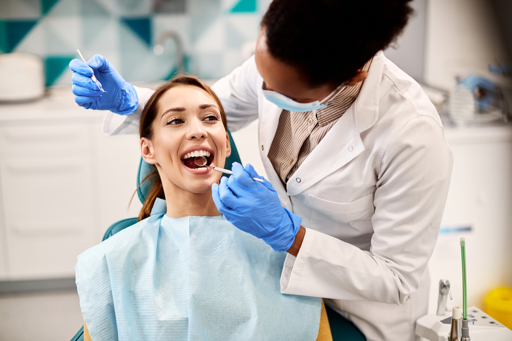 Dentist checking a smiling patient's teeth before a whitening treatment at a Norfolk dental office 