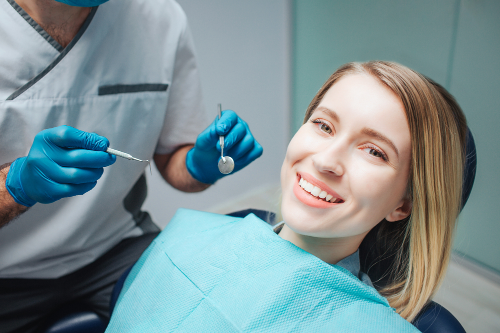 Denture and partial consultations in Norfolk Dentist holding examination tools while a smiling patient sits in the dental chair