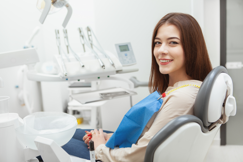 Smiling woman seated in a dental chair before a cosmetic dentistry visit in Virginia Beach 