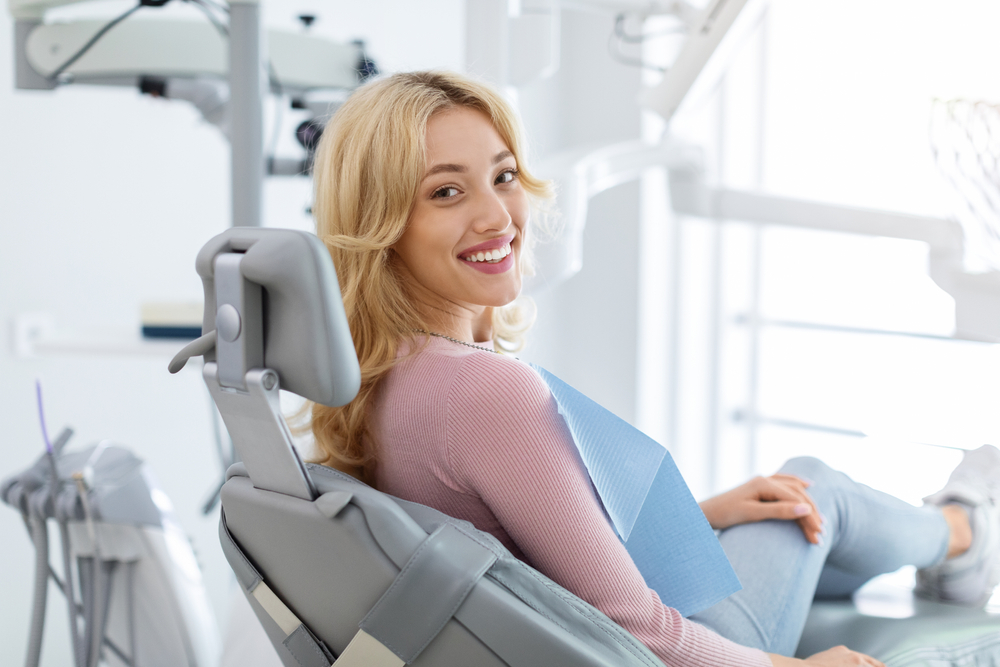 Woman smiling confidently in the dental chair during a dental implant consultation at The Foleck Center, Norfolk, VA 